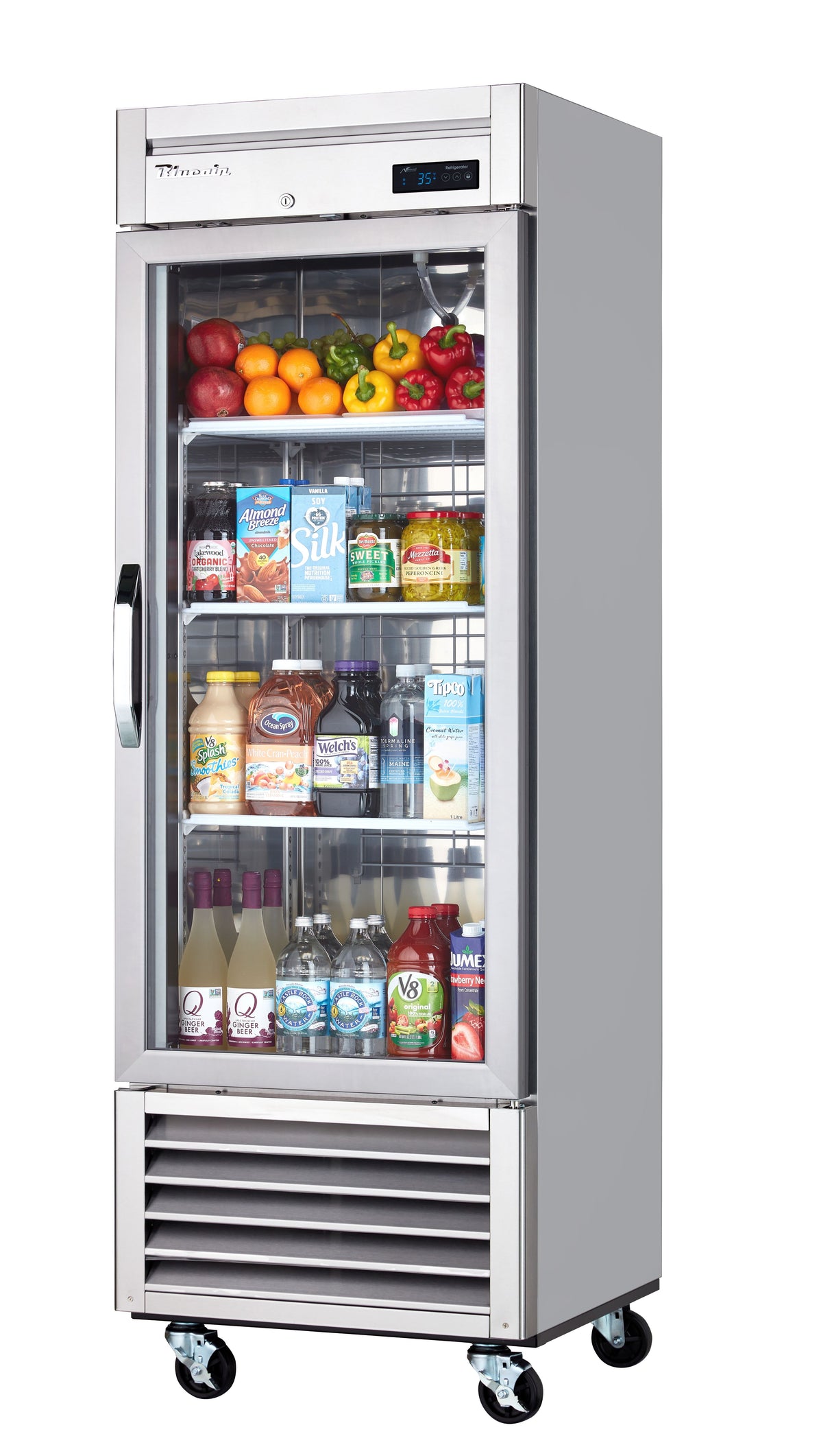 A commercial reach-in refrigerator on wheels contains assorted bottled drinks, cartons, sauces, and jars below, with fresh produce like peppers, tomatoes, apples, lemons, and lettuce on the top shelf. The digital display shows the temperature.