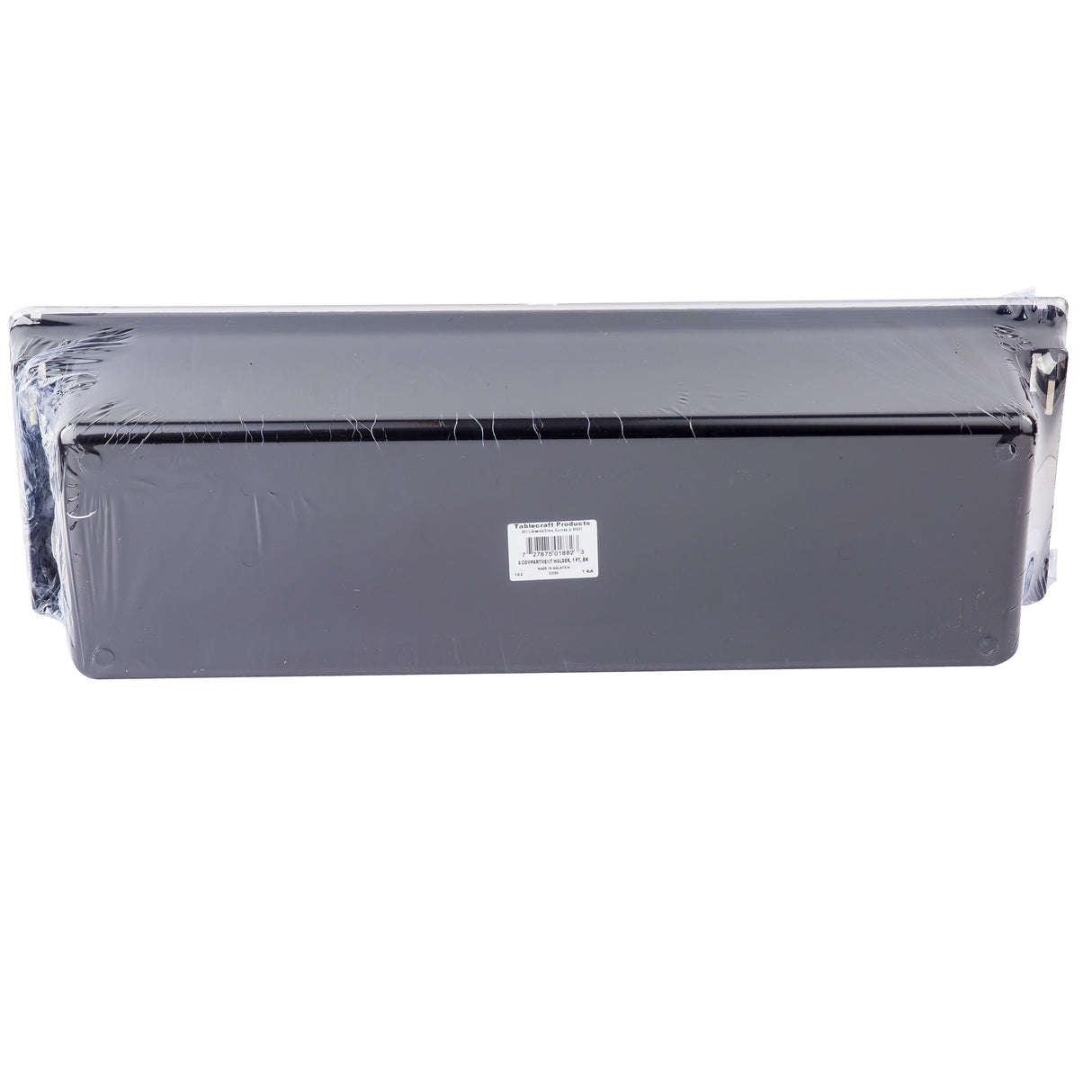 A rectangular black metal object, possibly a TableCraft bar condiment holder for 6 pint inserts, is wrapped in clear plastic. A white barcode sticker is centered on the front surface and the item is photographed against a plain white background.