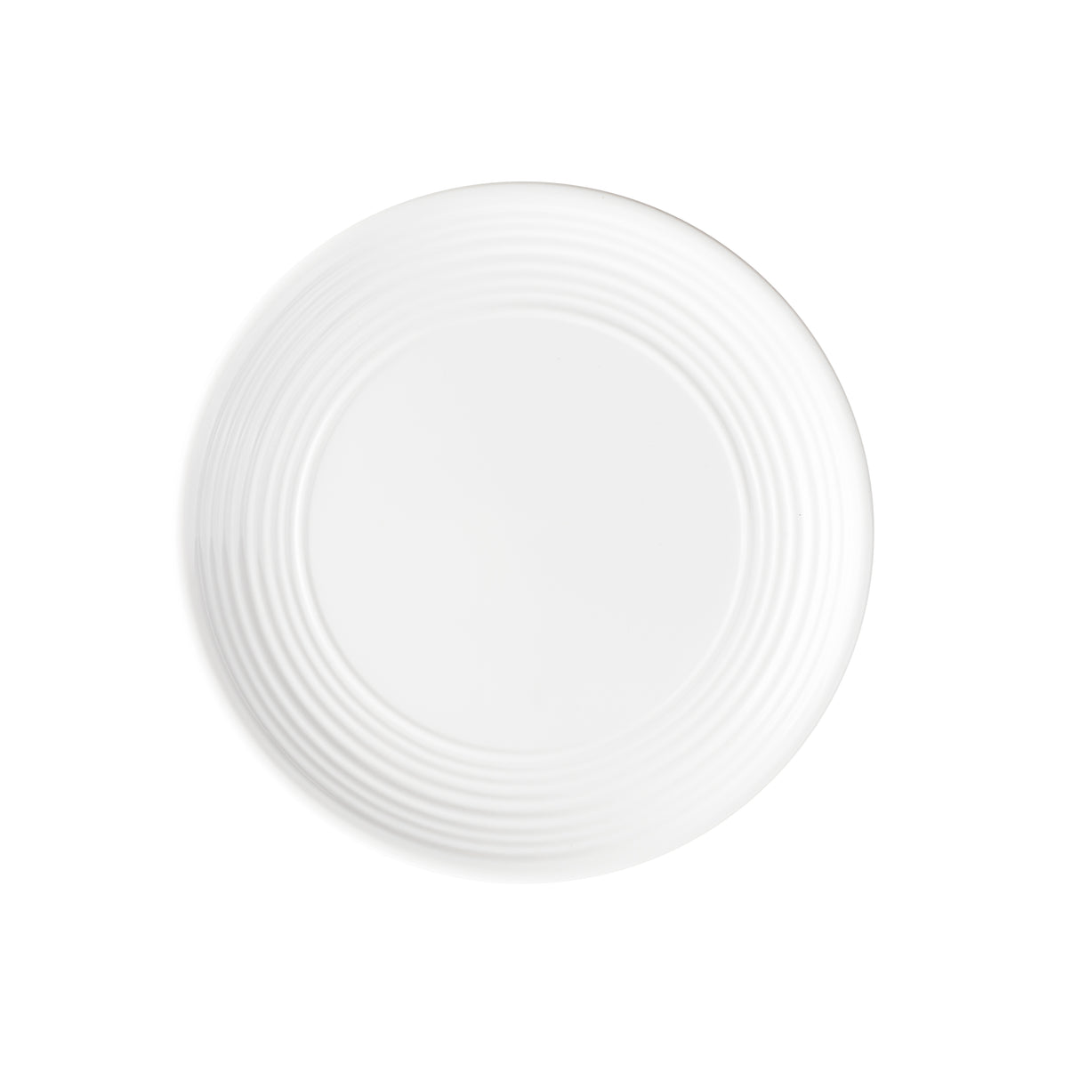 A plain white round plate from the Pulito Collection viewed from above. Its smooth melamine surface and concentric circular ridges on the outer edge add subtle texture, while the all-white background creates a clean, minimalist look.