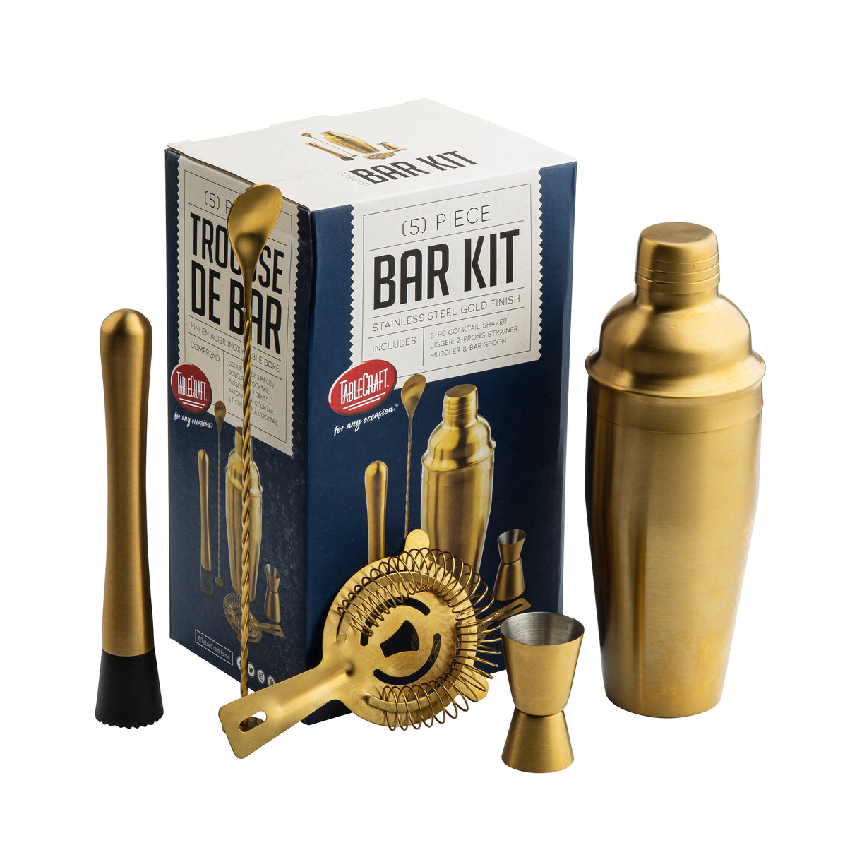 A gold-finished stainless steel bar kit is pictured with its box. The 5-piece set includes a cocktail shaker, muddler, bar spoon, strainer, and jigger, all in matching metallic gold, neatly arranged in front of blue and white packaging.