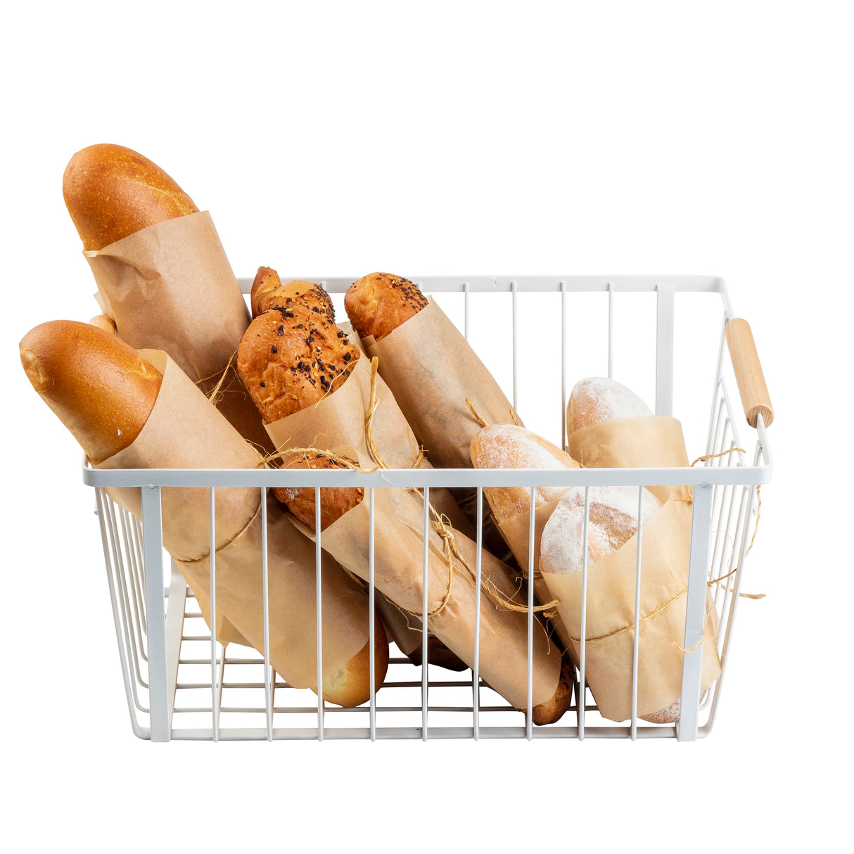 A white powder coated steel Storage Basket with wooden handles holds assorted baguettes and breadsticks wrapped in brown paper, each tied with string. The basket showcases various textures and colors of bread against a white background.