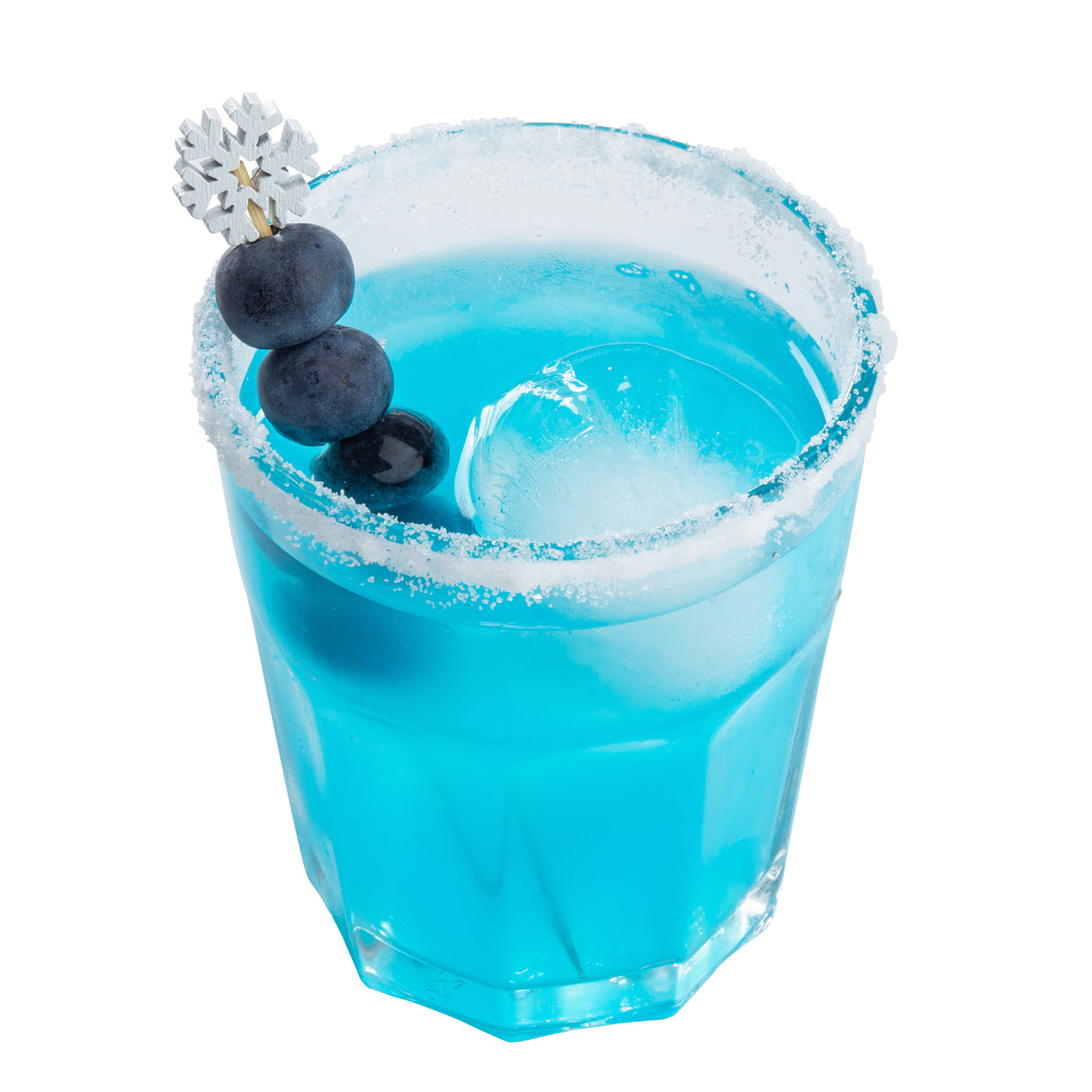 A glass of vibrant blue cocktail with a salted rim, large ice sphere, and three blueberries skewered on bamboo snowflake picks. Served in a faceted glass against a white background, it creates a frosty, refreshing appearance.