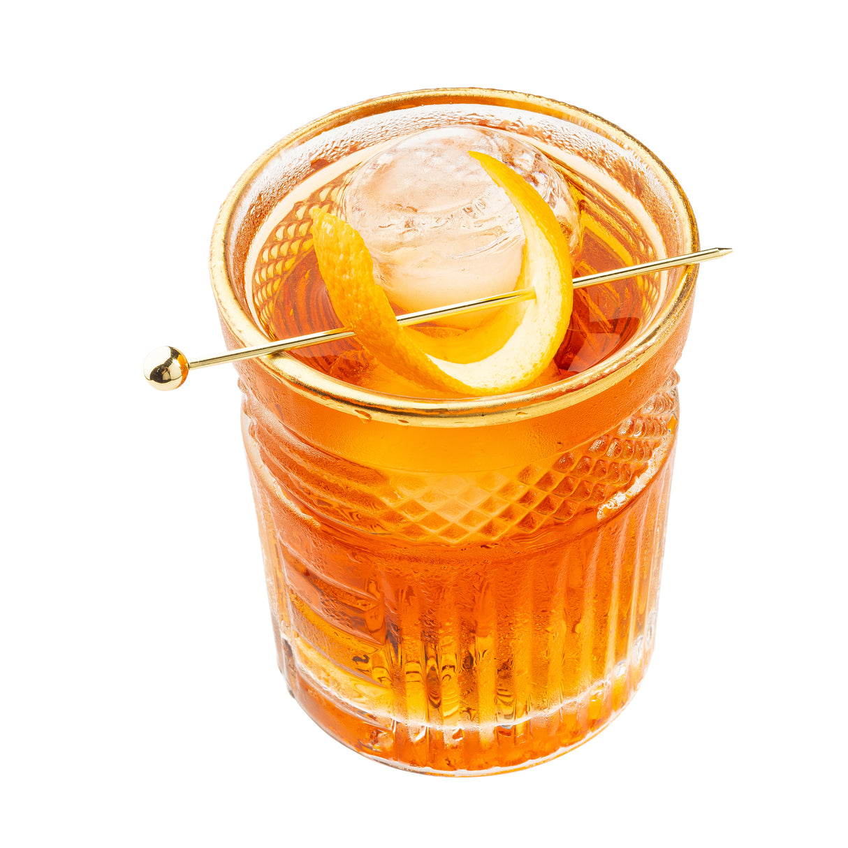 A clear, textured glass filled with an orange cocktail, garnished with a large ice sphere and a curled orange peel skewered on a gold cocktail pick, set against a white background with sleek stainless steel accents.