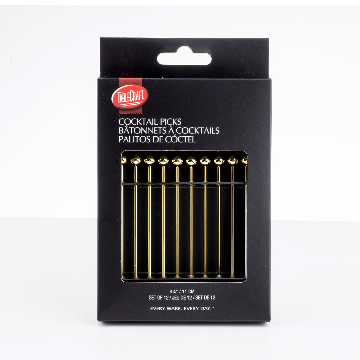 A black box of TableCraft cocktail picks is shown upright. The package displays 12 gold stainless steel picks with spherical tops visible through a window. White text on the box provides product name and details in English, French, and Spanish.