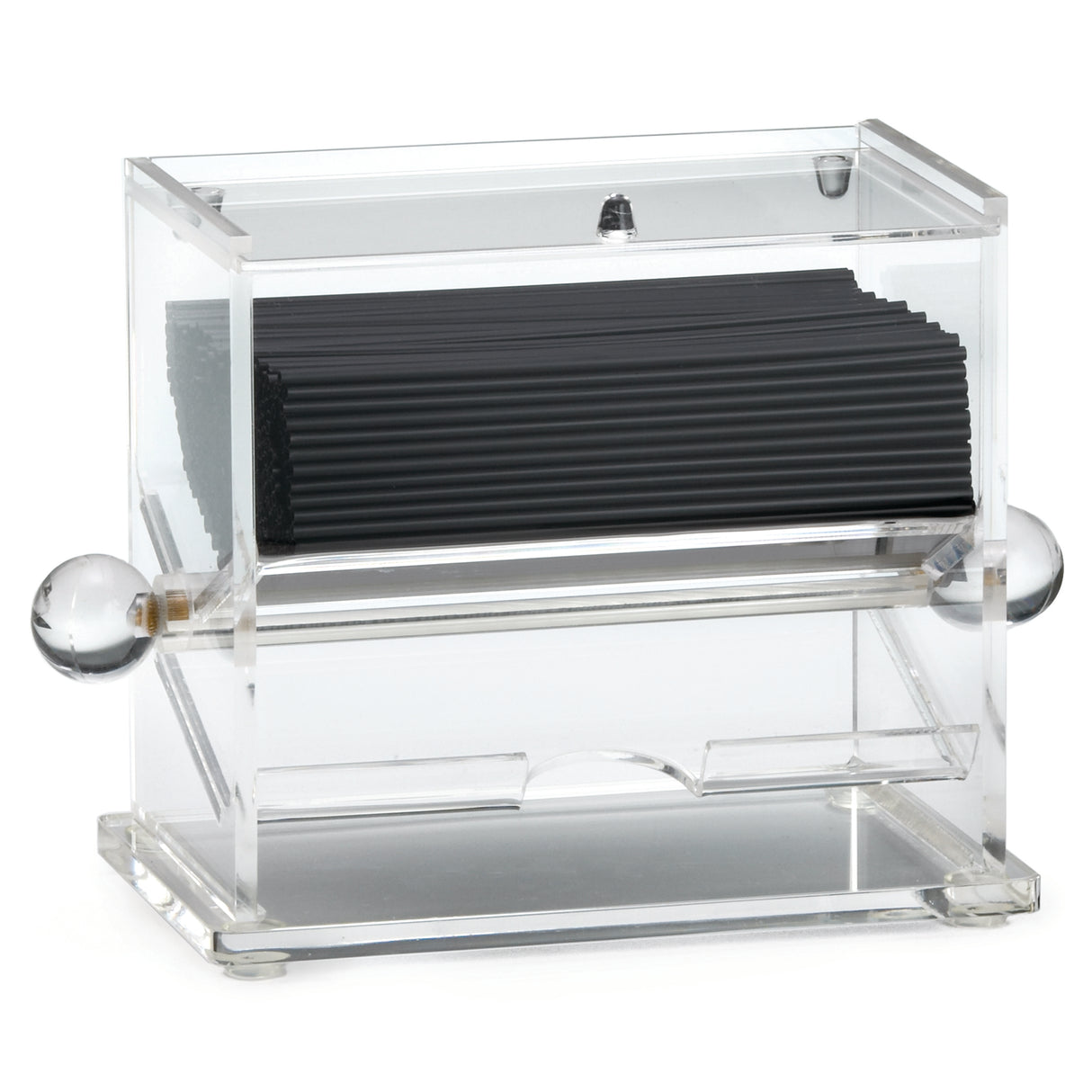 A clear acrylic stir stick dispenser holds a stack of black coffee stirrers. The box features rounded, clear knobs on both sides and an opening at the bottom front for easy access. Its modern, minimalist design complements any space.