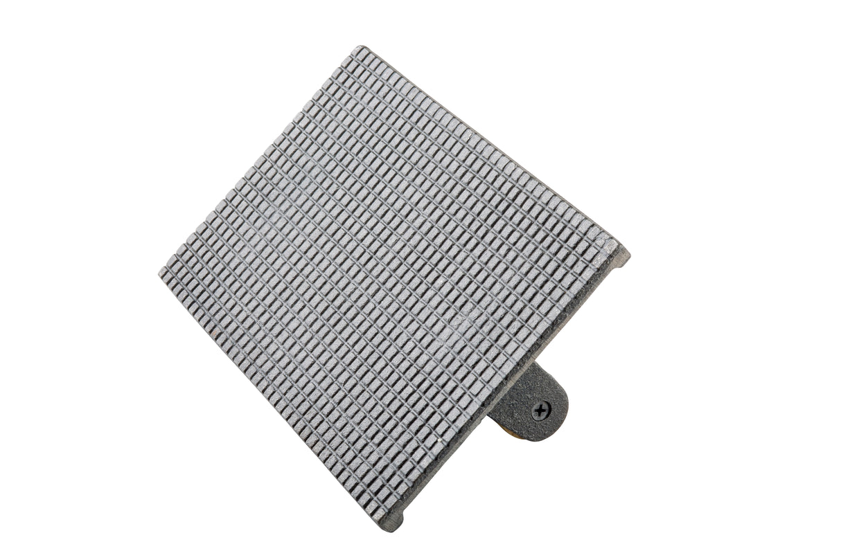 A rectangular cast iron object with a grid of small raised squares viewed at an angle. It has a mounting bracket and visible screw on the underside, against a white background. The object appears to be a textured plate, possibly a footplate or steak weight.