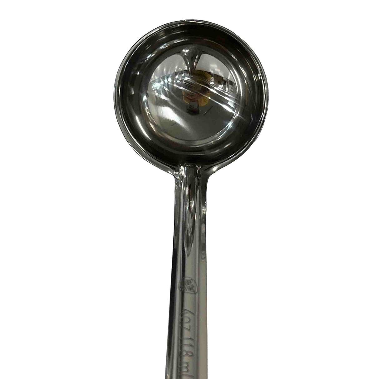 A shiny, dishwasher safe stainless steel measuring spoon with a round bowl and a long handle is shown on a white background. The reflective surface of the spoon displays some distorted reflections.