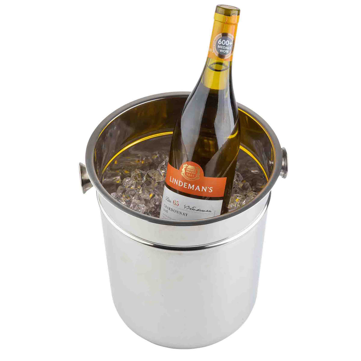 A bottle of Lindeman’s white wine chills in a stainless steel Wine/Champagne Bucket filled with ice cubes. The angled bottle displays its label clearly, while the bucket—dishwasher safe—features sturdy side handles against a plain white background.