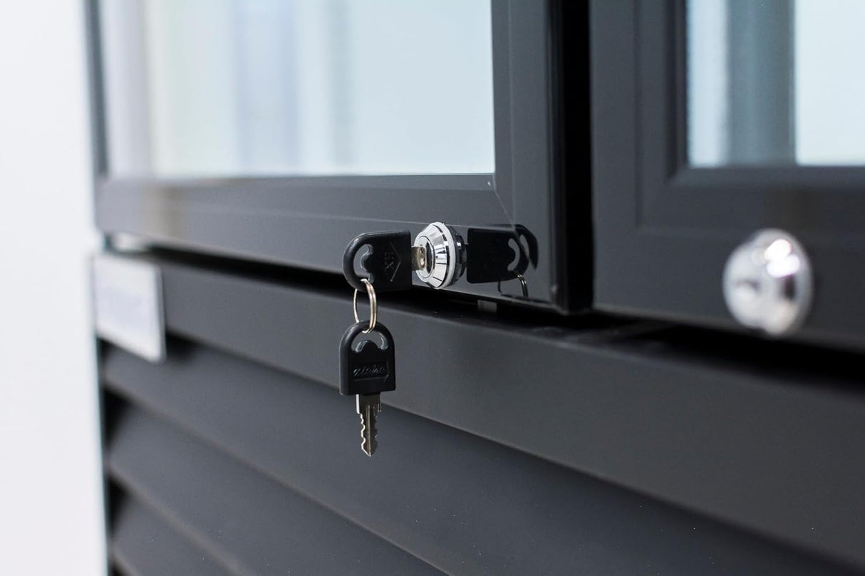 Close-up of a black-framed commercial refrigerated merchandiser, like the Empura EGM-50B, with a silver lock. A black key is inserted while another hangs on the ring. Reflections highlight part of the louvered panel below.