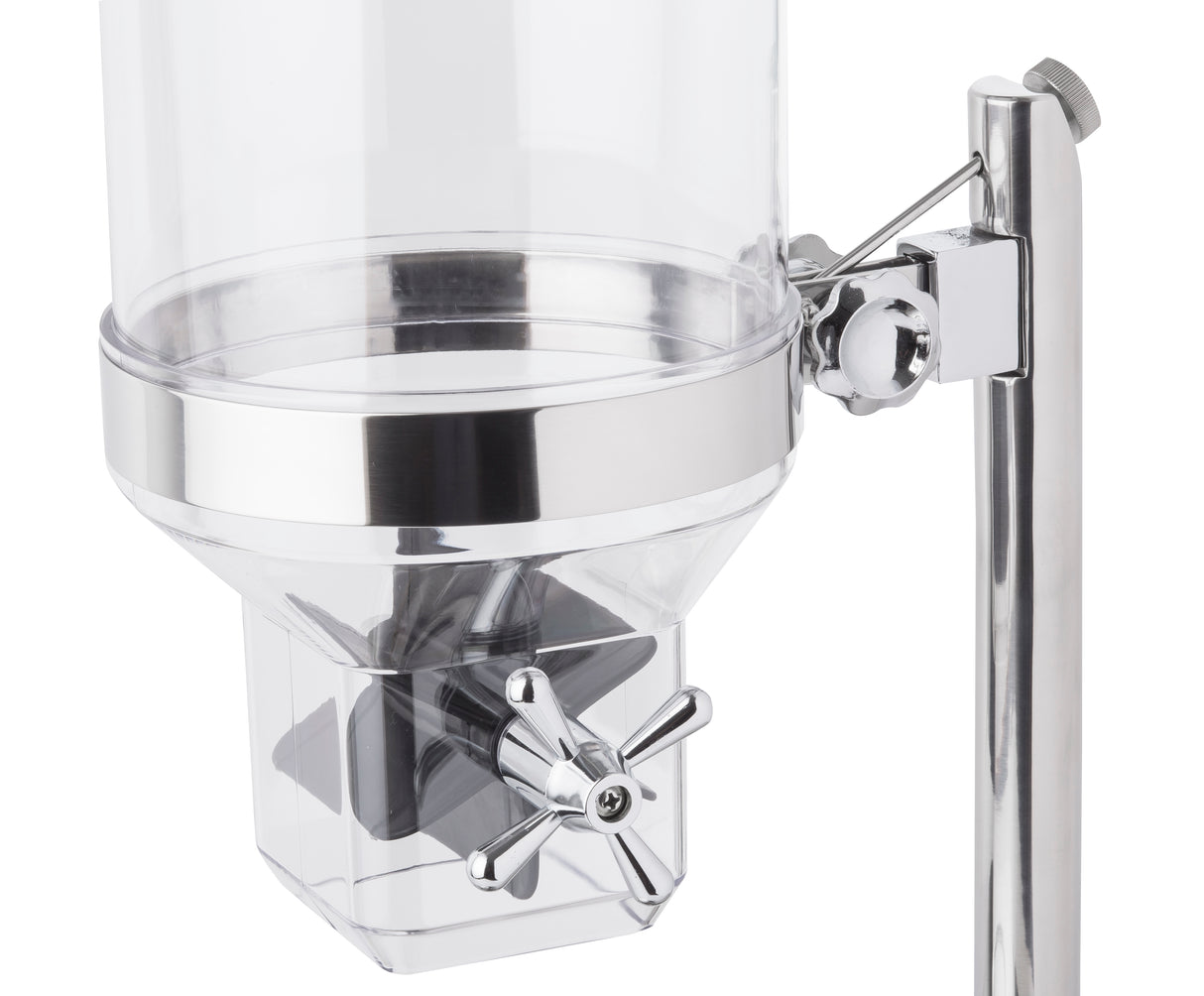 A close-up of a clear polycarbonate beverage dispenser with a cylindrical container, shiny metal accents, and a cross-shaped metal spigot handle attached to a vertical metal stand. The image focuses on the lower half and dispensing mechanism.