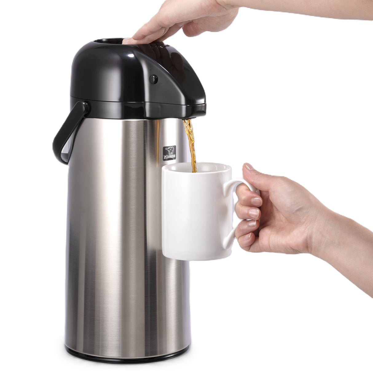 A person presses the top of a stainless steel Airpot, featuring a vacuum liner for superior heat retention, dispensing coffee or tea into a white ceramic mug held by another hand against a white background.
