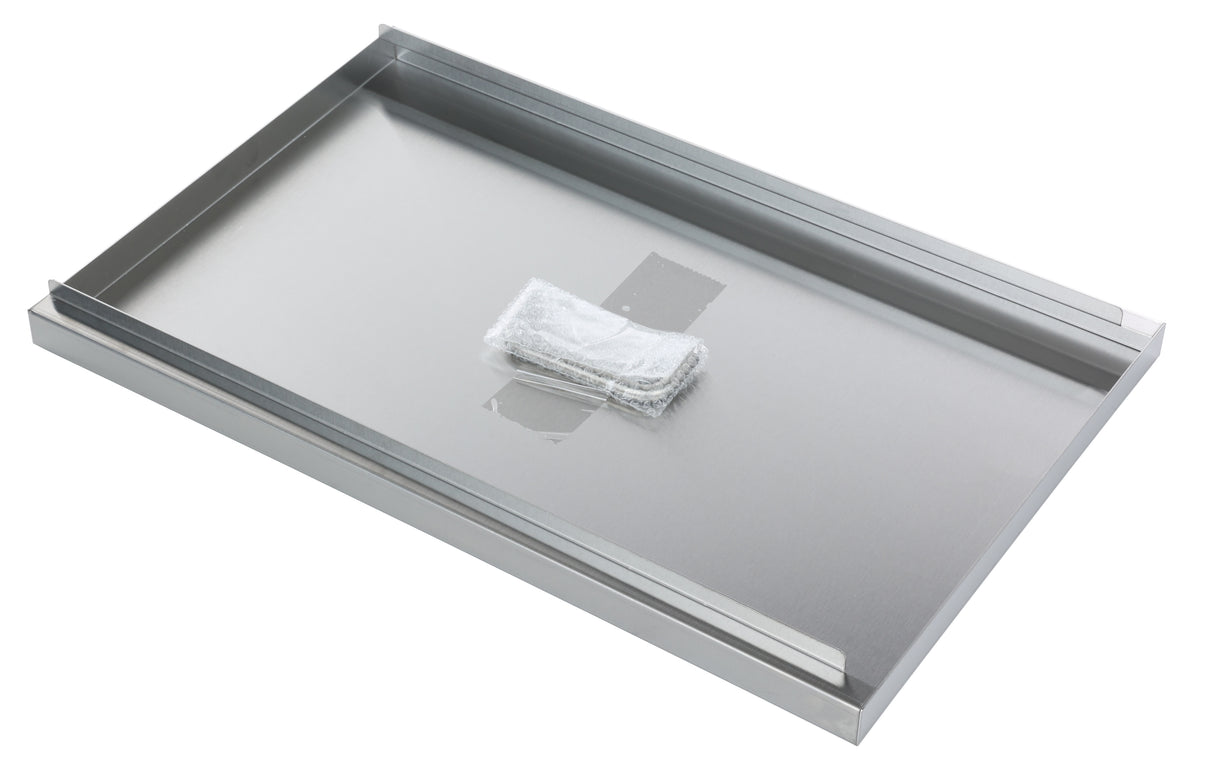 A rectangular stainless steel tray, similar to an ATFS-40 Fryer Tank Cover, lies flat with raised edges on two sides. A small, white, textured cleaning pad is secured near the center by translucent tape. The reflective surface appears clean and pristine.