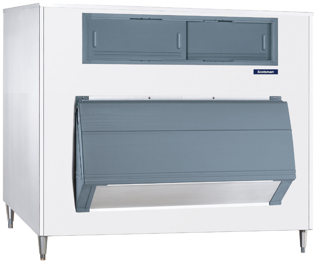 A commercial ice machine with a white exterior and gray front panel, featuring an upright ice storage bin. The unit stands on four metal legs and sports a small blue “Scotsman” label on the large angled door used for dispensing ice.