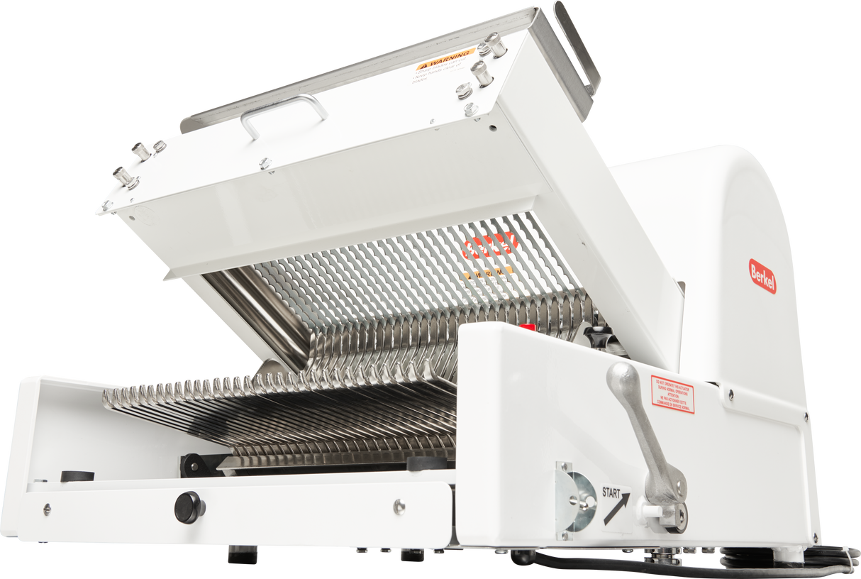 A commercial bread slicer with a white exterior, stainless steel cutting blades, and a lever on the side. The countertop machine’s top lid is open, revealing closely spaced blades for slicing loaves. The Redi logo is visible on the machine.