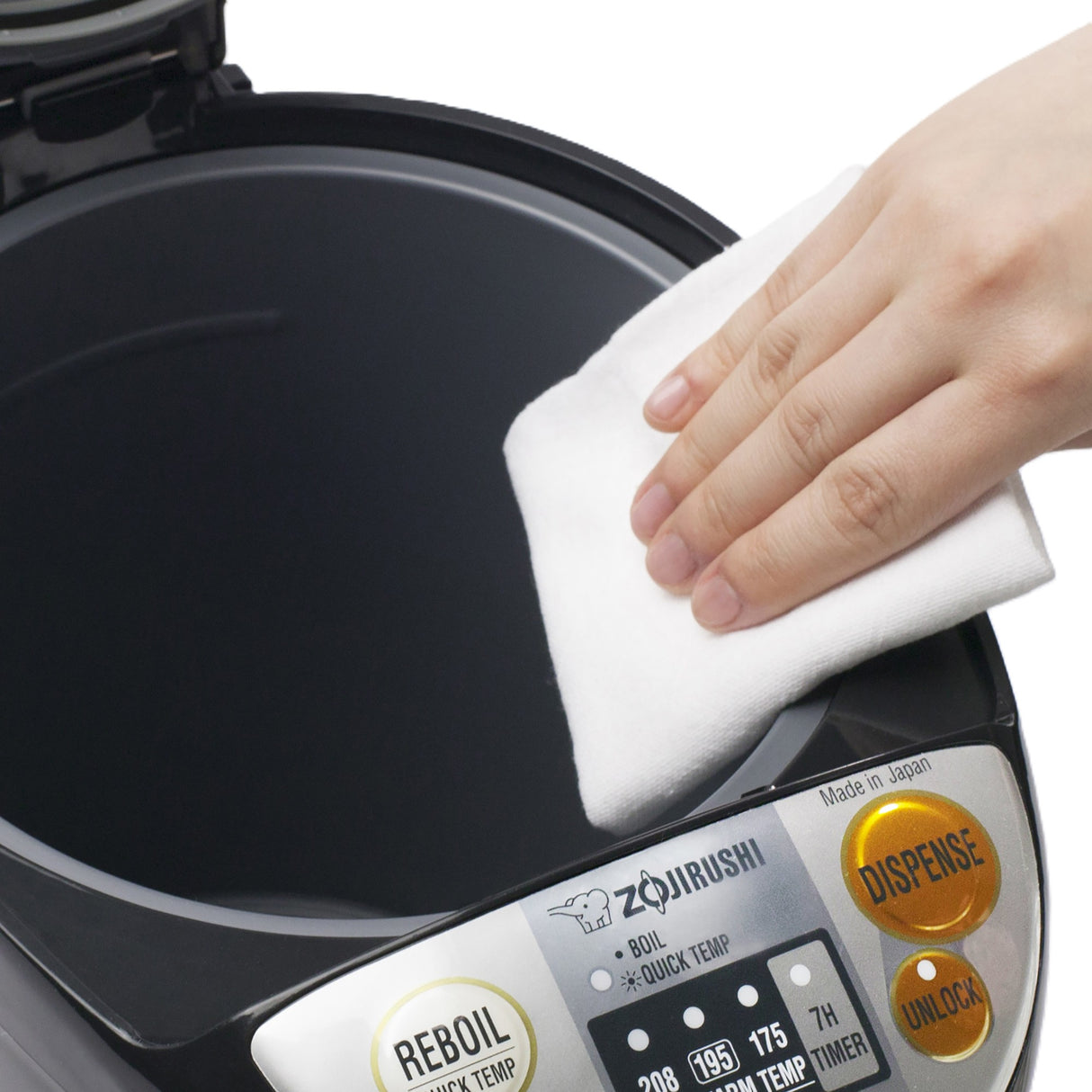 A hand wipes the inner surface of a 5 liters Zojirushi Water Boiler & Warmer with a white cloth. The open lid reveals a control panel featuring gold buttons labeled Reboil, Dispense, and Unlock.