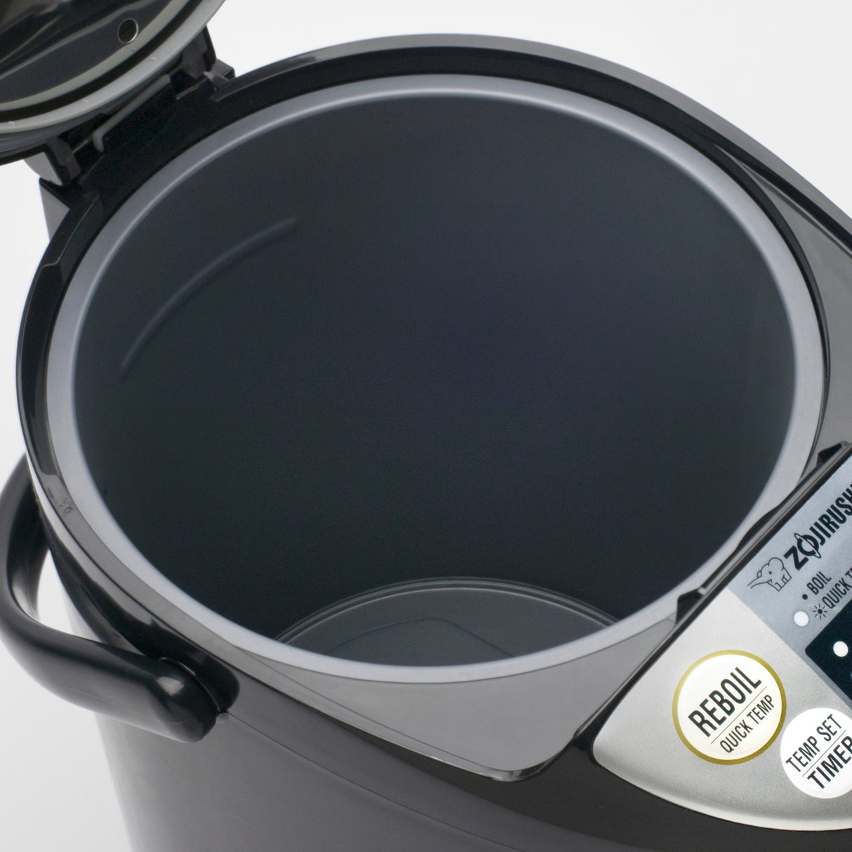 A close-up view of a Zojirushi 5 liters Water Boiler & Warmer, showing its empty gray inner container. Control buttons labeled REBOIL, TEMP SET, and TIMER are visible on the right side, and the mainly black device features a digital display.