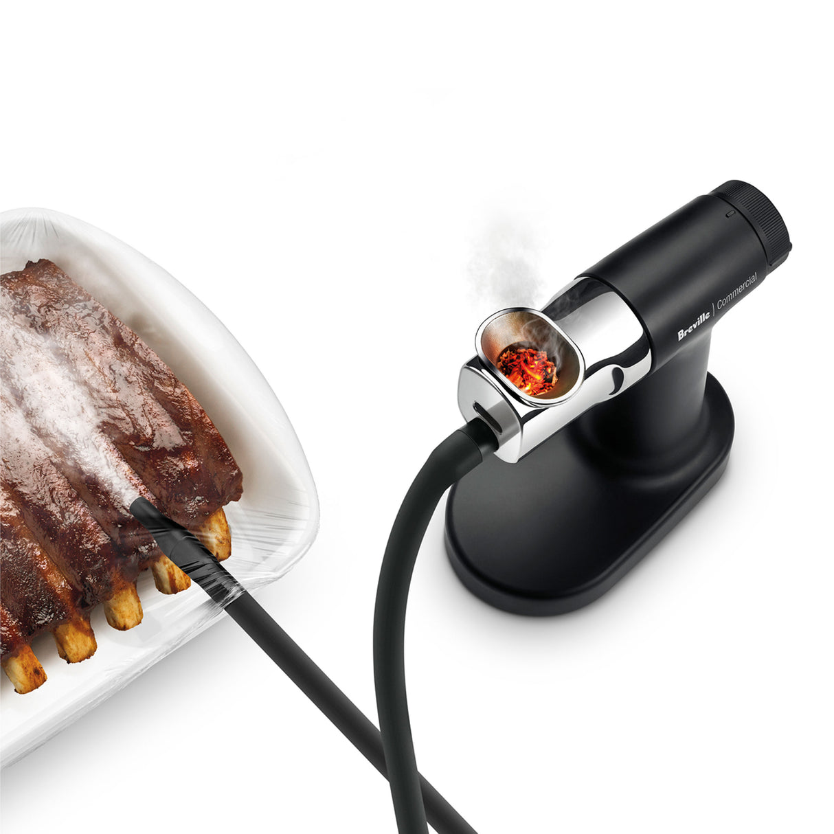 A handheld smoking gun pro device blows aromatic smoke through a tube onto a covered tray of ribs. With burning wood chips inside, this cold smoke infuser fills the clear plastic-wrapped container, flavoring the food with rich, smoky notes.