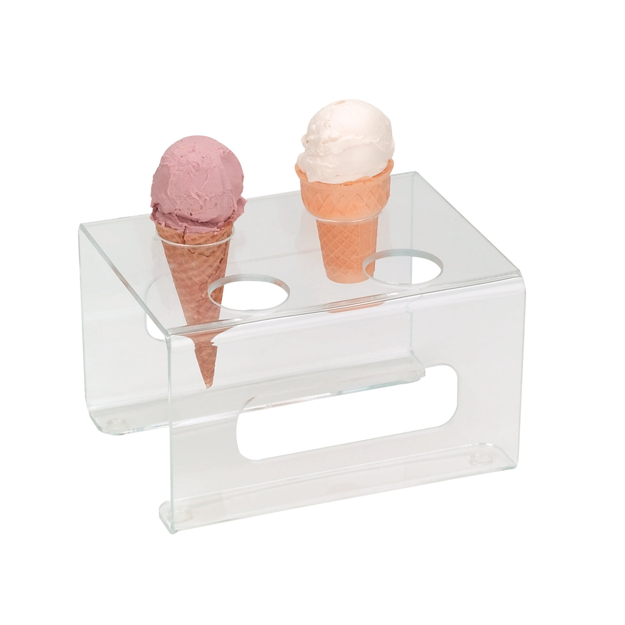 A clear acrylic cone holder with two circular holes keeps ice cream cones upright; one holds pink, the other white ice cream. The stand, similar to a Dispense-Rite CTCS-4C, rests on a white surface and has a rectangular cutout on the side.