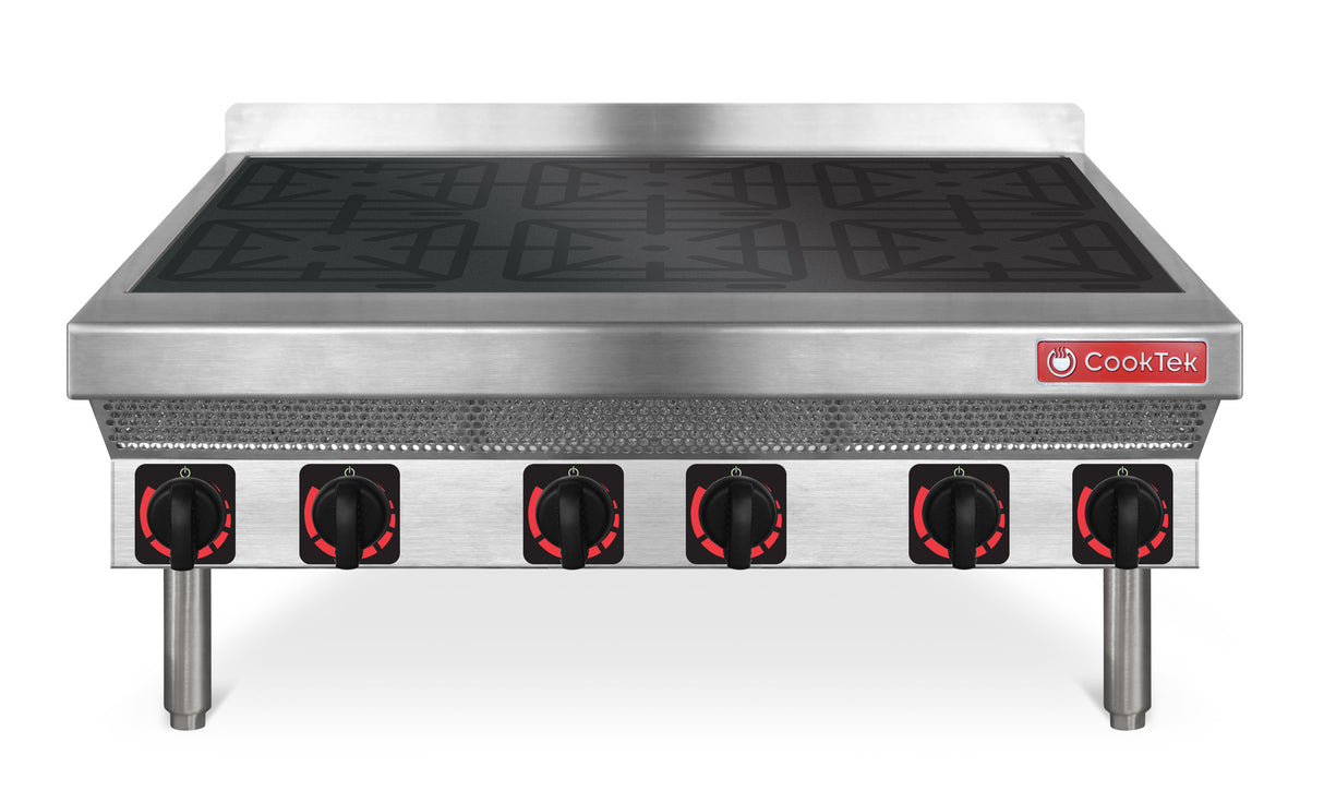 A stainless steel commercial induction range with six black and red control knobs, a black cooking surface with four burner zones, and the CookTek logo on the front right. The unit features sturdy cylindrical legs and a perforated metal front panel.