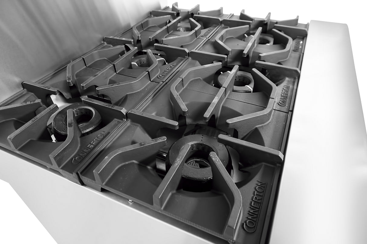 Close-up view of a stainless steel restaurant range with six black cast iron gas burners in two rows. The word “CONVETION” is embossed on the burners. The high-contrast black and white photo highlights this commercial kitchen centerpiece.