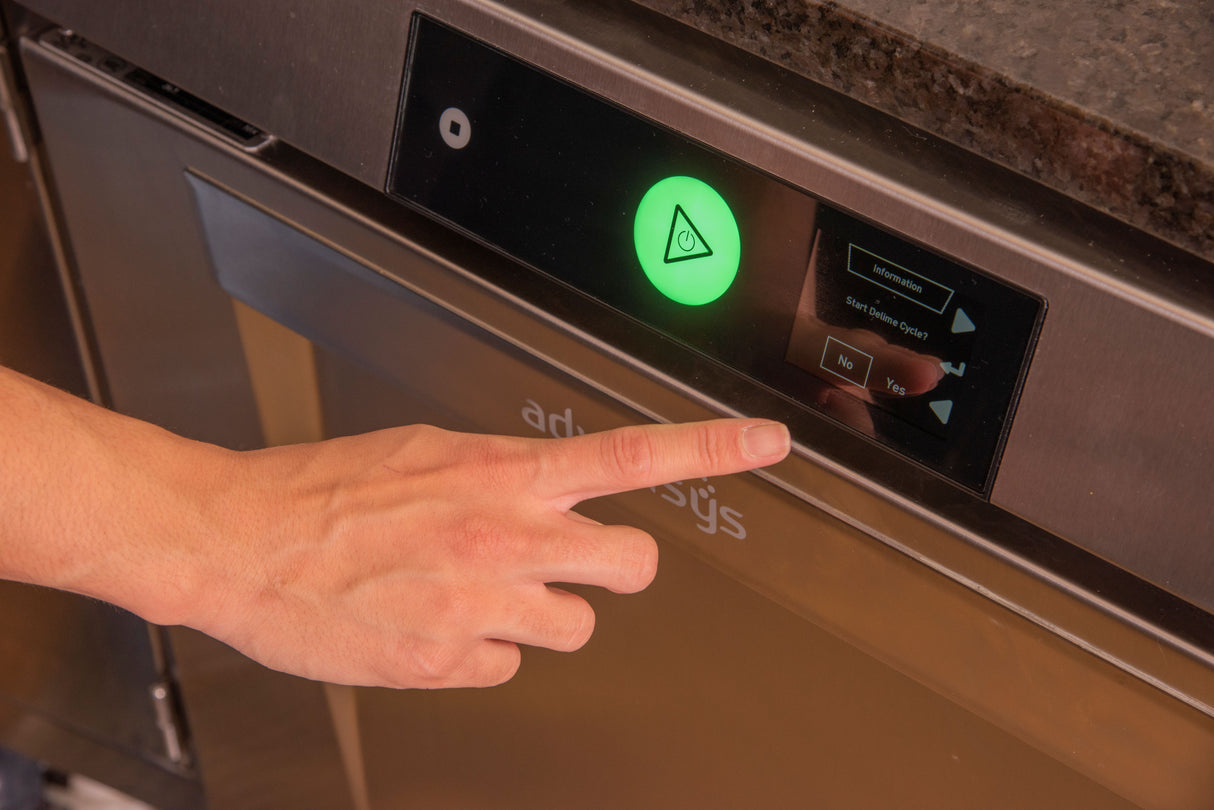 A person’s hand with an extended index finger is pressing a “Yes” button on the digital touch screen of an undercounter dishwasher. The screen displays a glowing green triangle and prompts to start the high temperature sanitizing cycle.