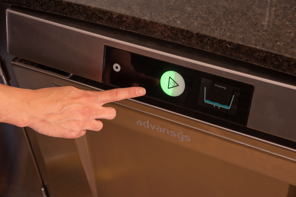 A hand with an extended index finger is about to press a large, illuminated green button with a triangle symbol on the stainless steel LXNH-2 undercounter dishwasher control panel. The display screen shows Draining and an icon of high temperature sanitizing.