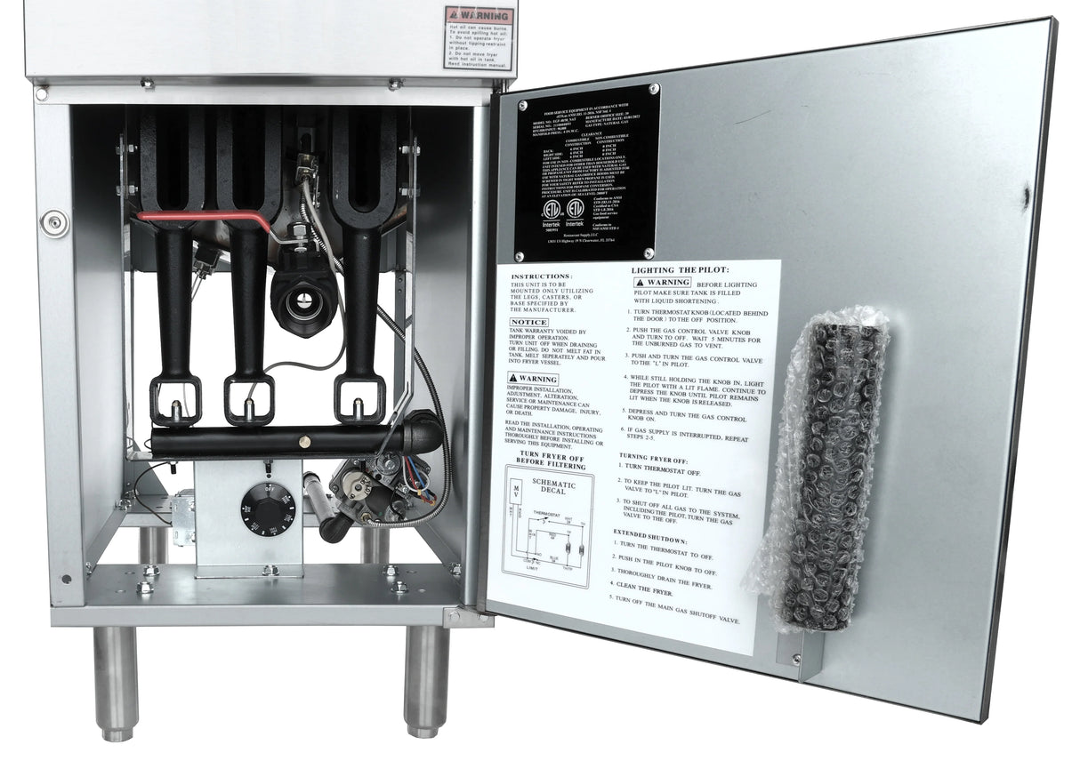 Industrial metal appliance, likely a commercial gas fryer, with the front panel open, revealing internal black pipes, wiring, control valves, and a gas regulator. The open door displays operating instructions and a packaged 40 lb capacity component wrapped in bubble wrap.