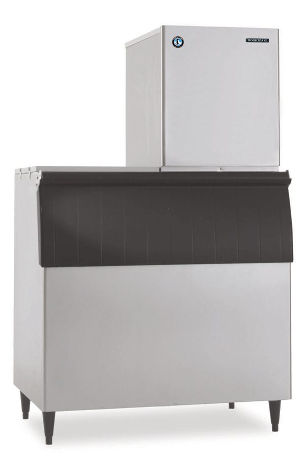 A large commercial cubelet ice maker, like the Hoshizaki F-1002MWJ-C, features a tall, boxy stainless steel water-cooled ice maker on top and a black-lidded storage bin below, complete with a circular logo and rectangular nameplate.