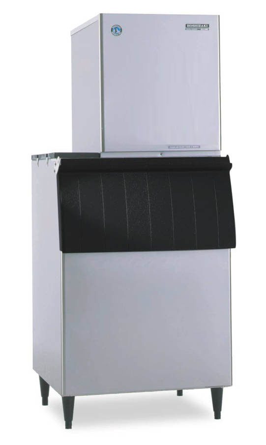 A Hoshizaki commercial Ice Maker featuring a tall, silver rectangular top unit and large black-fronted storage bin, stands on four legs. The flake-style machine boasts clean lines and a durable stainless steel finish for a boxy, modern look.