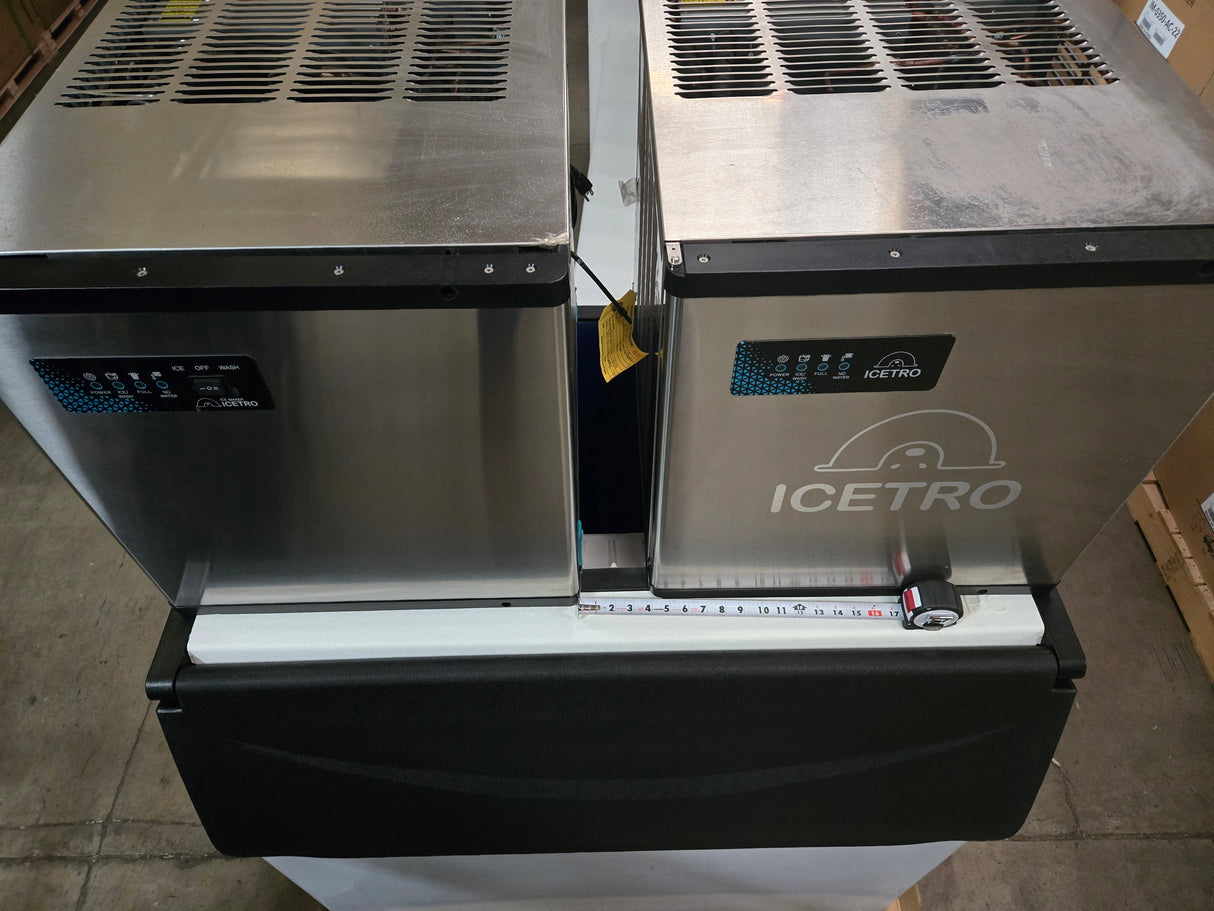 Two stainless steel ICETRO America ice machines with 22" heads sit side by side on a black base. Each features digital display panels, logo branding, a temperature control dial, and a measurement strip on the front edge. Bin adapter is included.