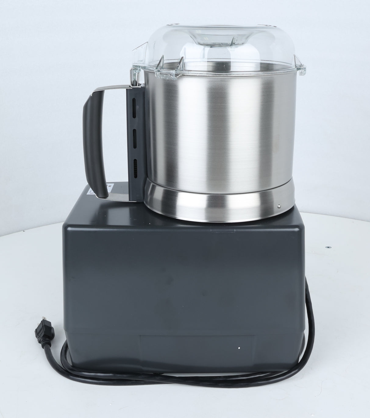 A large, industrial stainless steel commercial food processor—with a clear plastic lid—sits on a rectangular black base. The machine has a black handle, and an unplugged power cord extends from the base, coiled loosely on a white surface. Perfect for vegetable prep in busy kitchens, this Robot Coupe R301U.D ensures efficient and reliable performance.