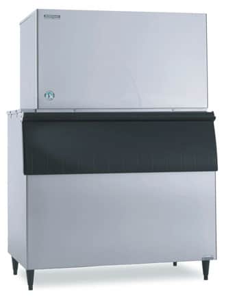 A large Hoshizaki cube-style ice maker with a stainless steel exterior and black front panel. The unit stands on four legs and features a modern, utilitarian design, making it ideal for industrial or restaurant use.