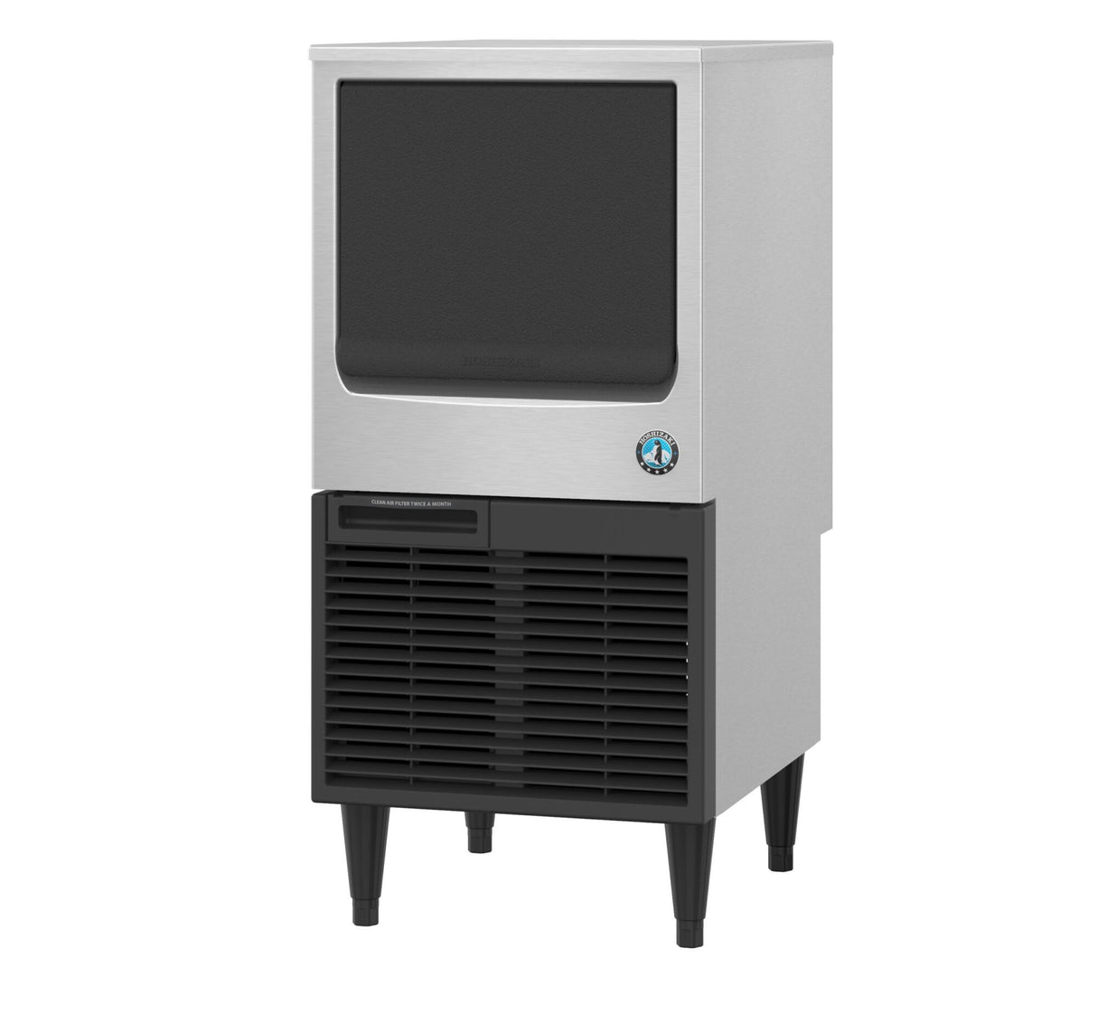 A stainless steel and black commercial ice maker stands on four tall legs. The upper section has a large, black door, while the lower front features black vented panels and a small blue and white circular logo near the door’s bottom right corner.