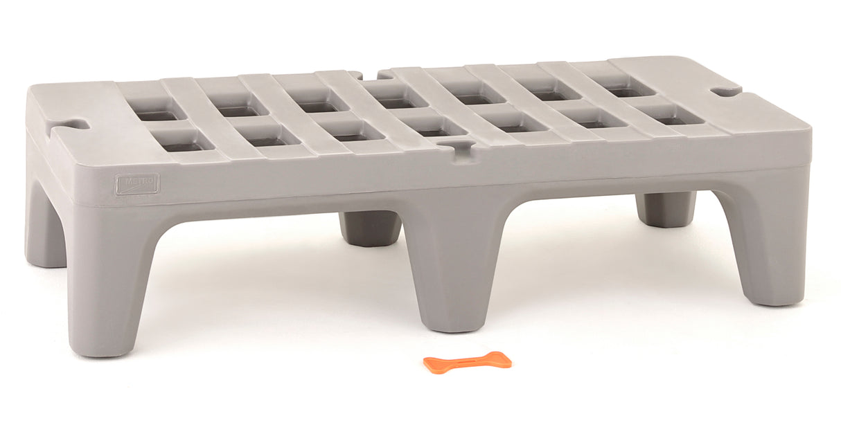 A gray, rectangular plastic step stool, similar to a small NSF dunnage rack, features four wide legs and a grid-patterned top on a white background. In front of the stool lies a small orange bone-shaped object.