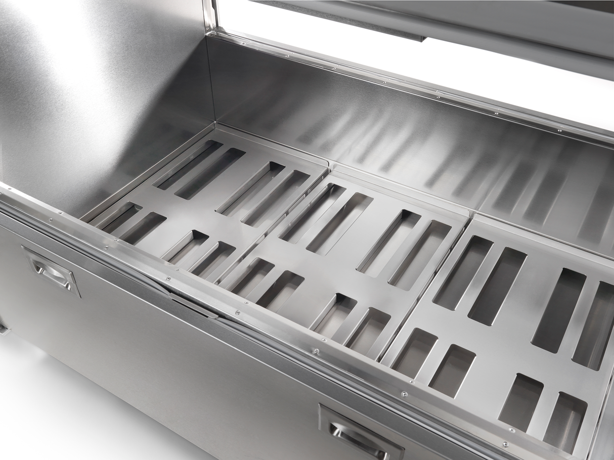 A close-up view of an open, empty stainless steel container with a hinged lid, reminiscent of a milk cooler. The interior features three removable metal trays with evenly spaced rectangular slots. The surface is clean, reflective, and industrial in design.