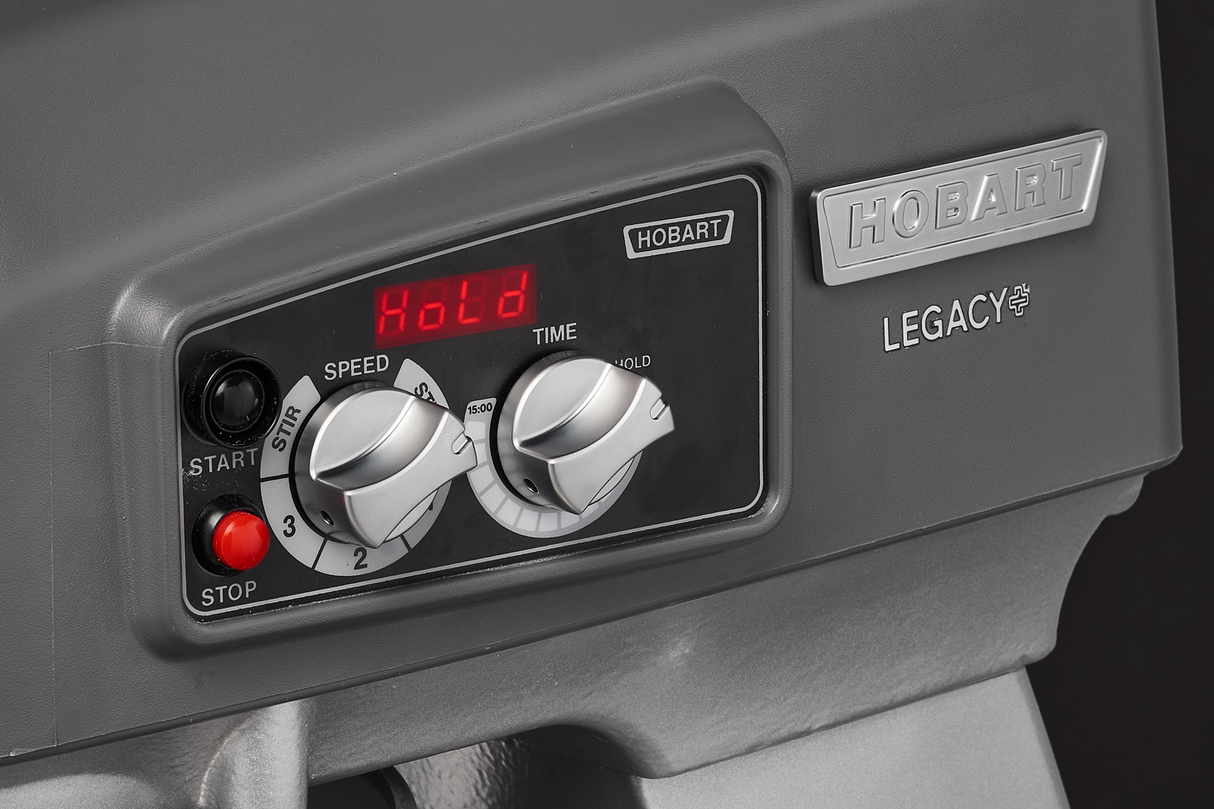 Close-up of a gray Hobart Legacy planetary mixer control panel showing two dials labeled “Speed” and “Time,” a digital display reading “Hold,” and buttons for “Start” and “Stop.” The panel also features Hobart branding on the machine.