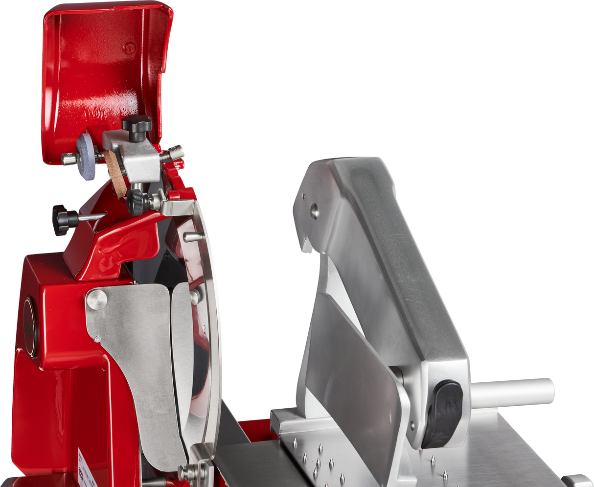 A close-up view of a red and silver Berkel Fly Wheel Slicer features its chromium-plated carbon steel knife, blade guard, and adjustable thickness knob. The upper protective cover is open, revealing the clean inner mechanism against a black background.