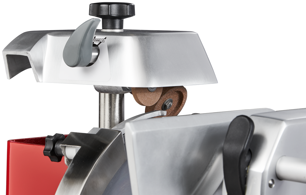 Close-up of a Berkel Fly Wheel Slicer’s blade sharpening mechanism, featuring a chromium-plated carbon steel knife, metal and plastic parts, a brown sharpening stone, adjustment knobs, and a red section against a black background.