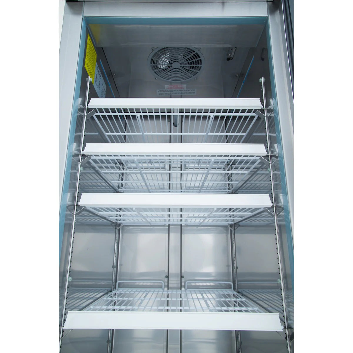 A photo showing the interior of an empty Empura Refrigeration reach-in refrigerator with five metal wire shelves and a fan at the top rear. The shelves are evenly spaced, and the metallic, reflective walls enhance its professional appearance.