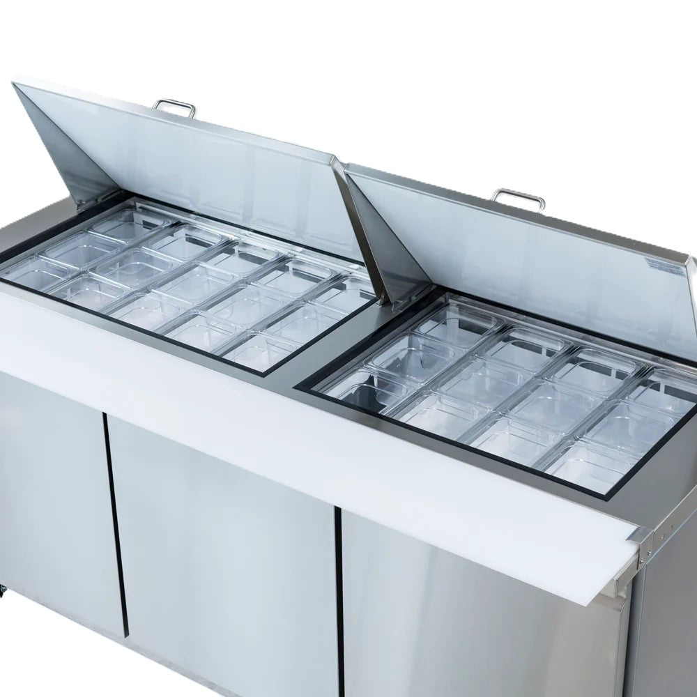 A stainless steel refrigerated sandwich prep table with two open top lids reveals multiple transparent ingredient containers. The table features a white cutting board along the front edge and three closed lower cabinet doors for storage.