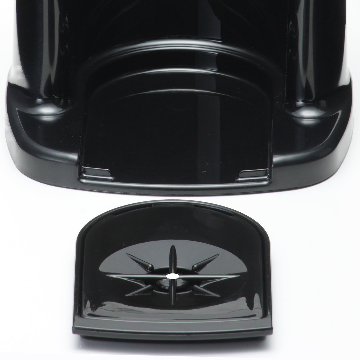 A close-up of a black plastic beverage dispenser base with a curved, detachable drip tray in front. The drip tray features a raised star-shaped pattern and central hole, designed to catch spills from the insulated appliance above. The surface is shiny and reflective.