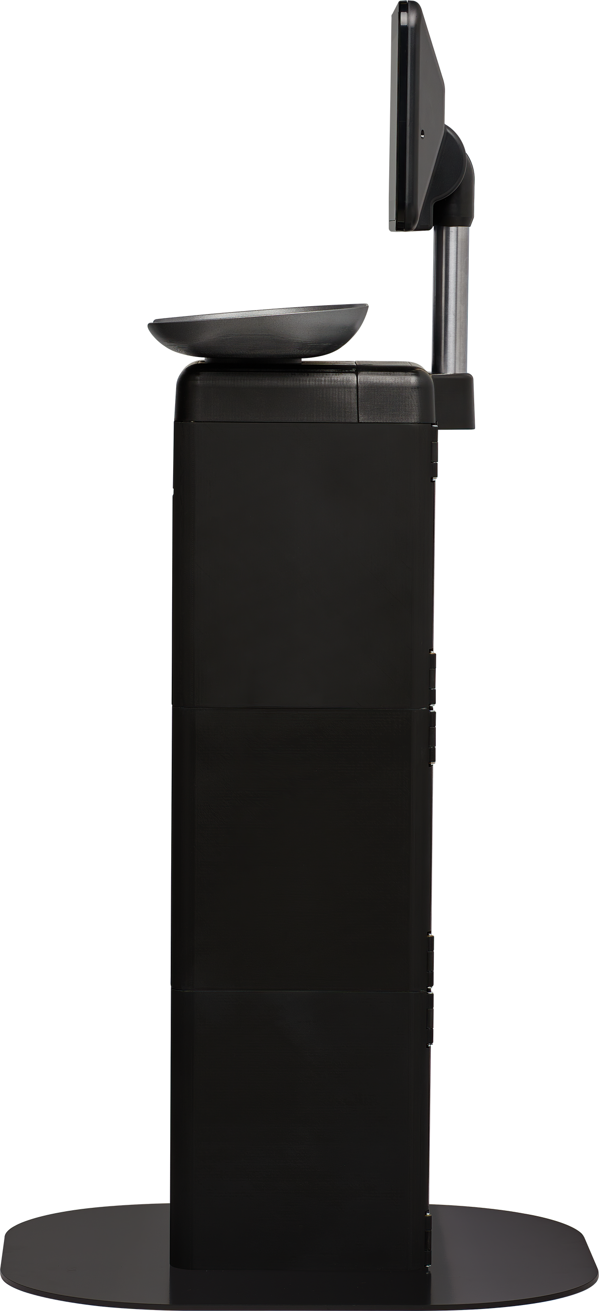 A side view of a black Self-Serve Scale kiosk with a flat base, vertical rectangular body, angled touchscreen display at the top, and a small tray below the screen. The kiosk stands alone on a circular platform.