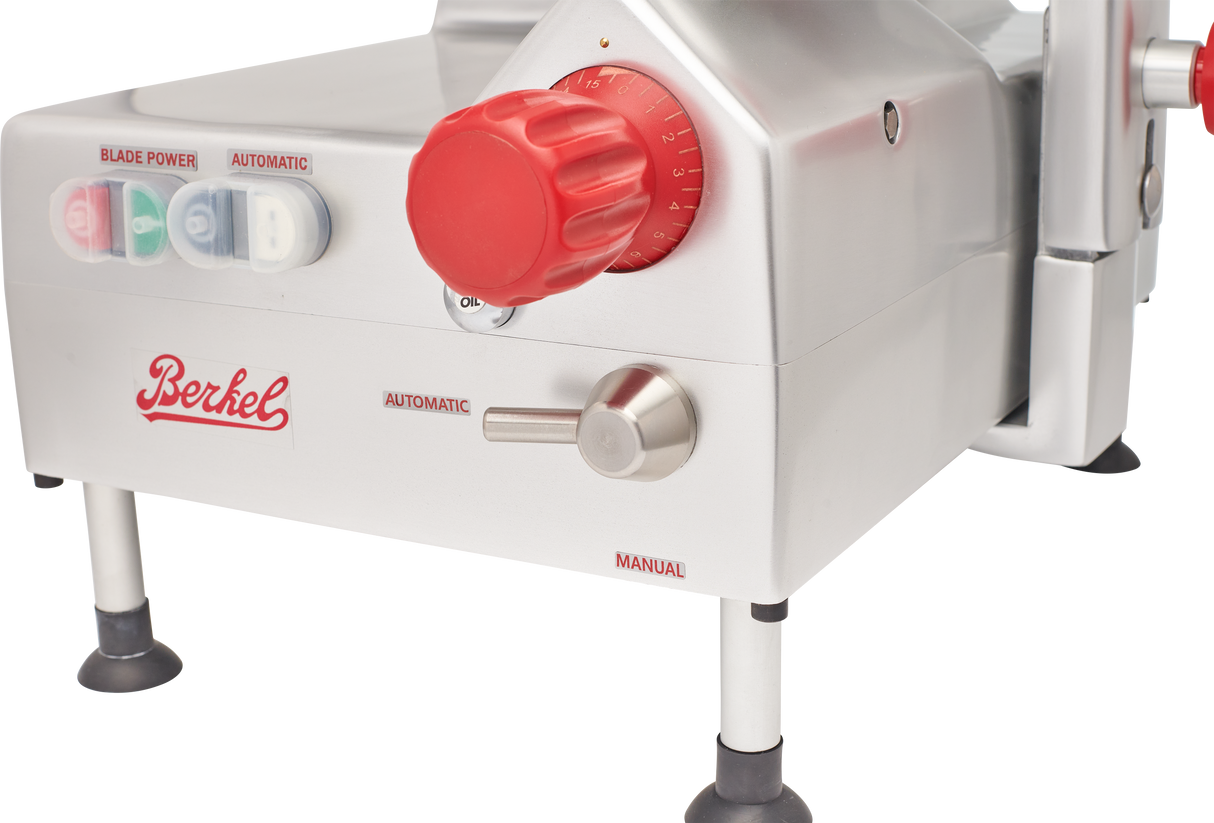 A close-up of a Berkel automatic slicer, featuring its front panel with a large red dial, a metal switch labeled Automatic and Manual, and buttons for blade power. This gravity feed slicer has a 12 carbon steel knife and sleek silver housing with bold red accents.