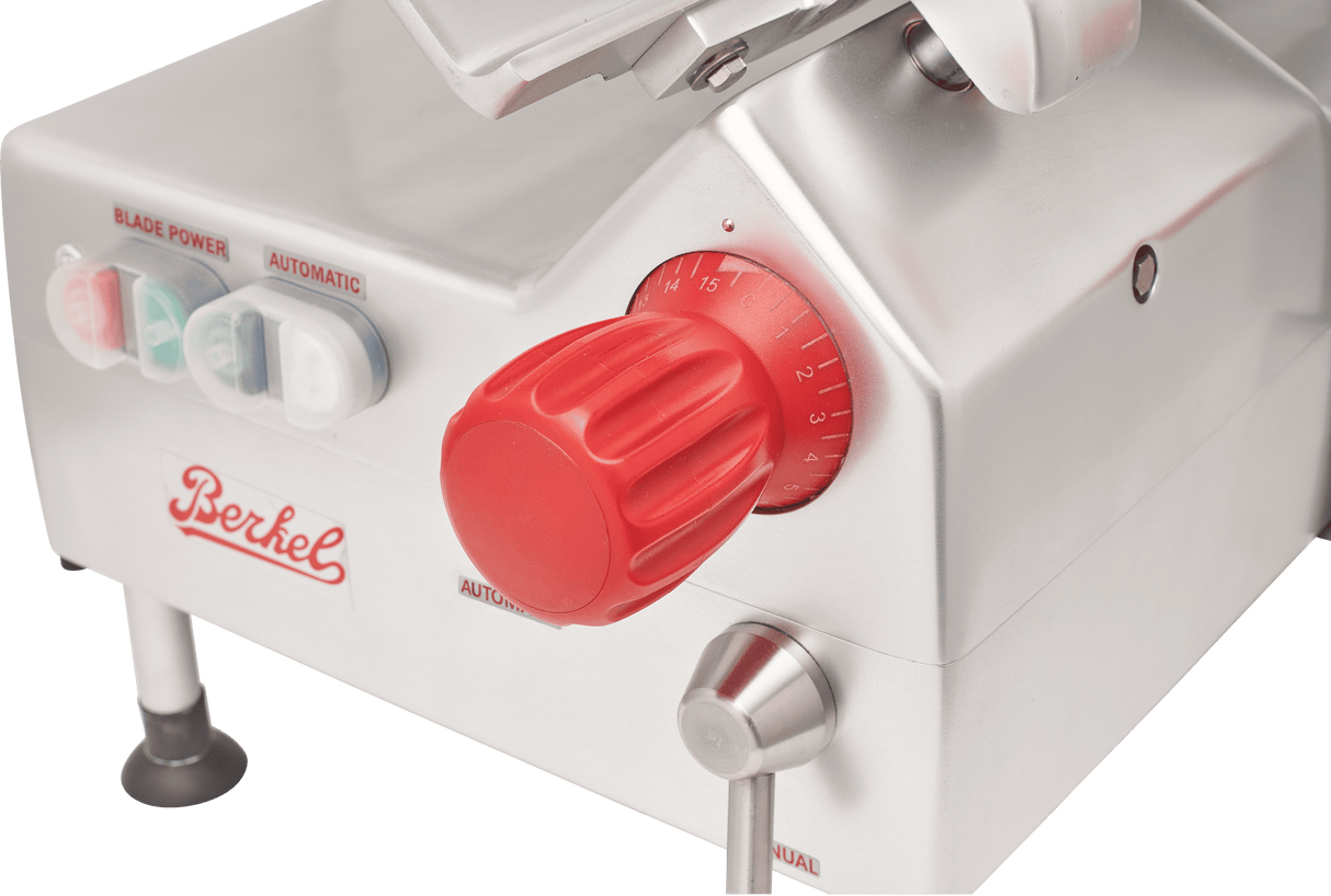 Close-up of a Berkel automatic slicer, featuring a large red dial with numbered settings, power and blade buttons, and a silver metallic body with the Berkel logo in red. This gravity feed slicer includes control buttons for “Blade,” “Power,” and “Automatic.”.
