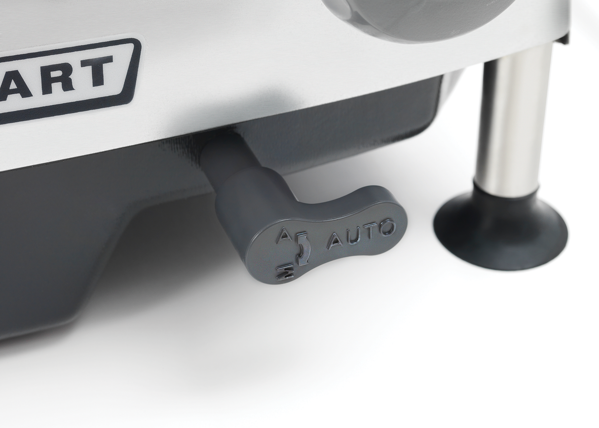 Close-up of a black plastic lever labeled “AUTO” with an arrow and steaming cup icon, attached to an automatic meat slicer. Part of a logo with ART and metal legs with black rubber feet are visible in the background.