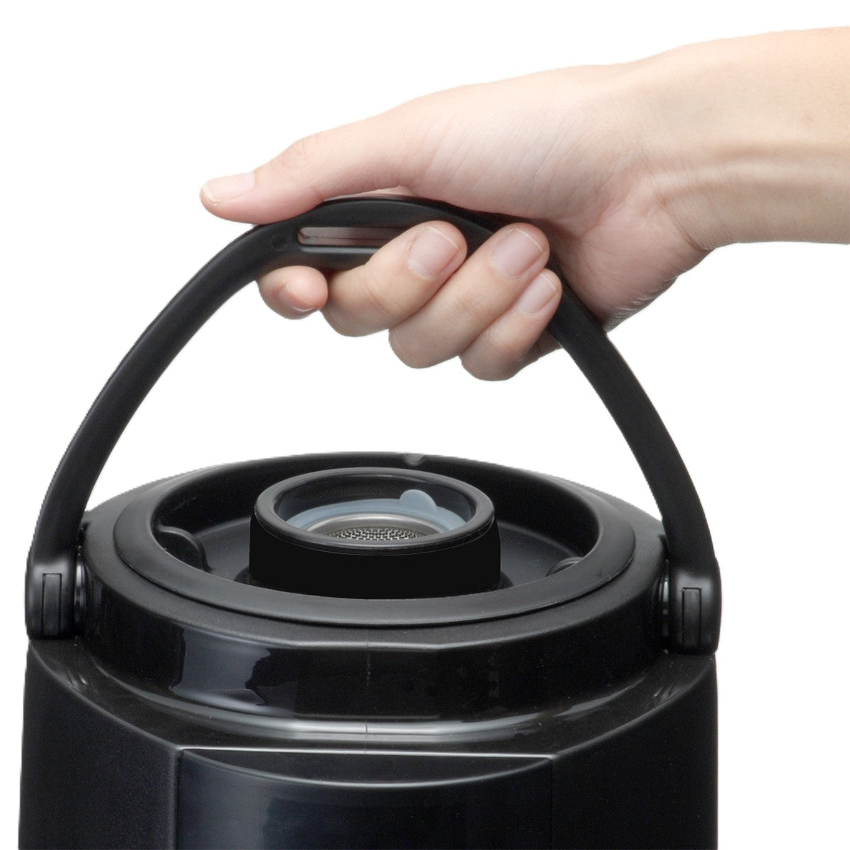 A hand grips the curved handle of a black insulated beverage dispenser. The jug’s lid features a gray rubber seal and a recessed area. This close-up highlights the thermos's upper part against a plain white background.