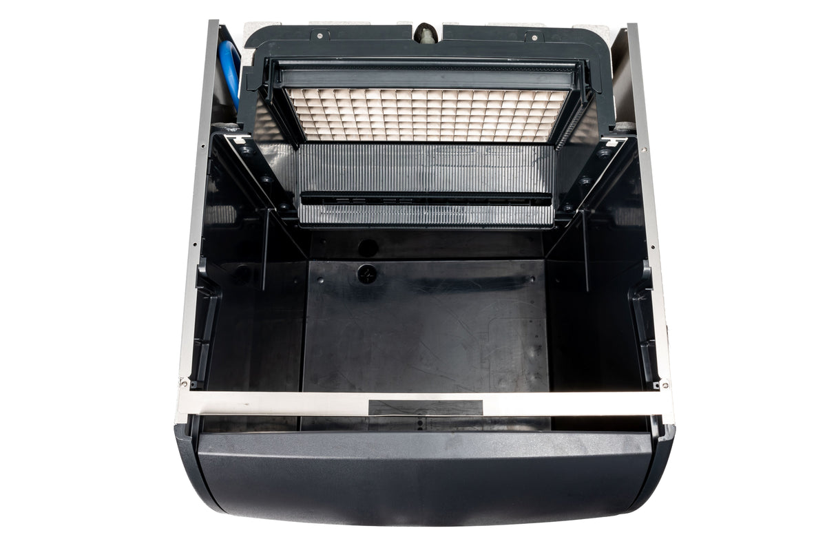 A top-down view of an open, empty black plastic container from a cube style ice maker, with a rectangular filter attached inside the upper part. The filter has a white grid pattern, and the clean interior reveals metallic side rails against a white background.