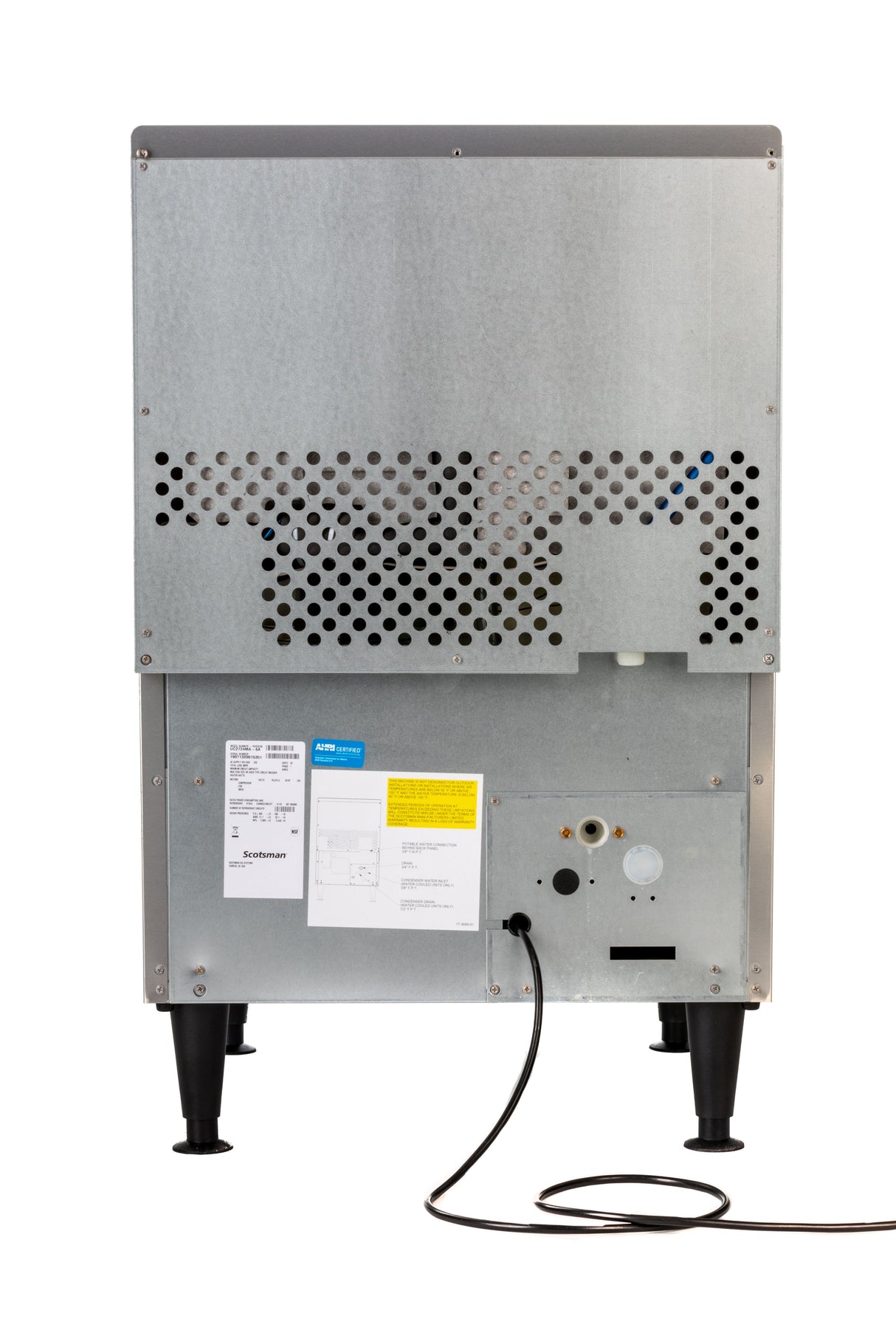 A metallic undercounter ice maker viewed from the back, featuring a perforated panel, a power cord attached to a lower socket, black adjustable legs, and several labels with text and diagrams affixed to the bottom section. The machine stands on a white background.