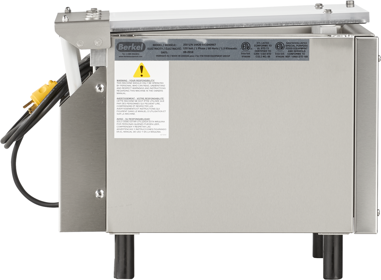A stainless steel commercial appliance, the Berkel 250-STD Vacuum Packaging Machine features a single stainless steel chamber, a power cord with yellow plug, warning labels, black legs, and a white section on top. The Berkel brand is visible on the upper left.