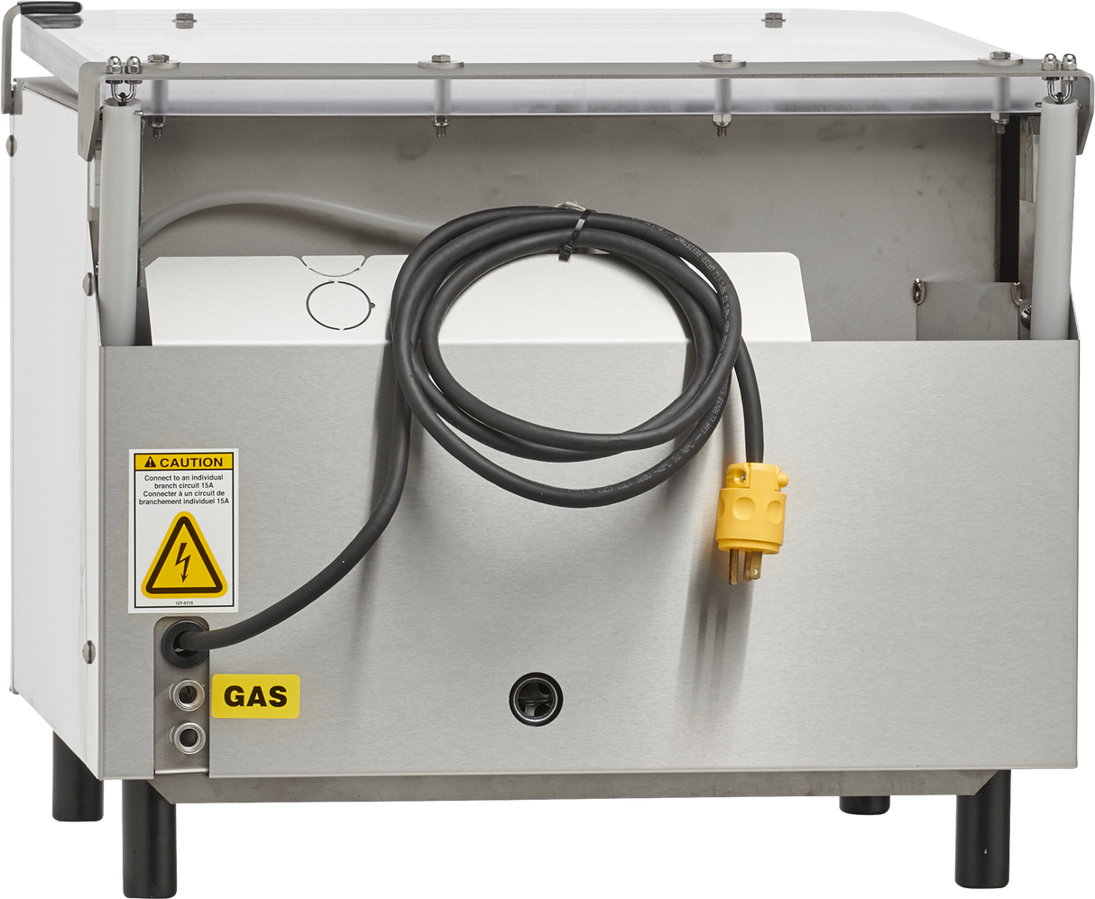 A stainless steel Berkel Vacuum Packaging Machine with a single chamber features an open front displaying electrical components, a coiled black cable with a yellow plug, caution labels for electrical hazard and gas, various connection ports below, and a slightly lifted top lid.